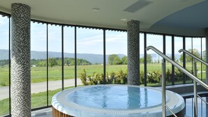 Un bain à remous offrant une vue panoramique sur un paysage verdoyant et des montagnes.