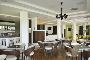 Ein modernes Restaurant mit hohen Decken, einer Bar und einer Sitzordnung mit Tischen und Stühlen.