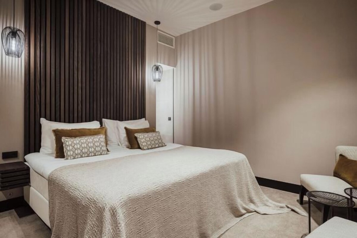 A modern bedroom with a large bed, a bedside table, and a chair.