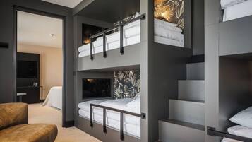 Ein modernes, mehrstöckiges Schlafzimmer mit Etagenbetten, einem Flachbildfernseher und einer gemütlichen Sitzecke.
