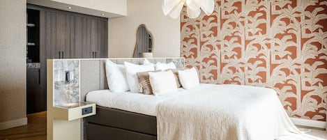 A modern bedroom with a bed, a nightstand, a wardrobe, and a patterned wallpaper.