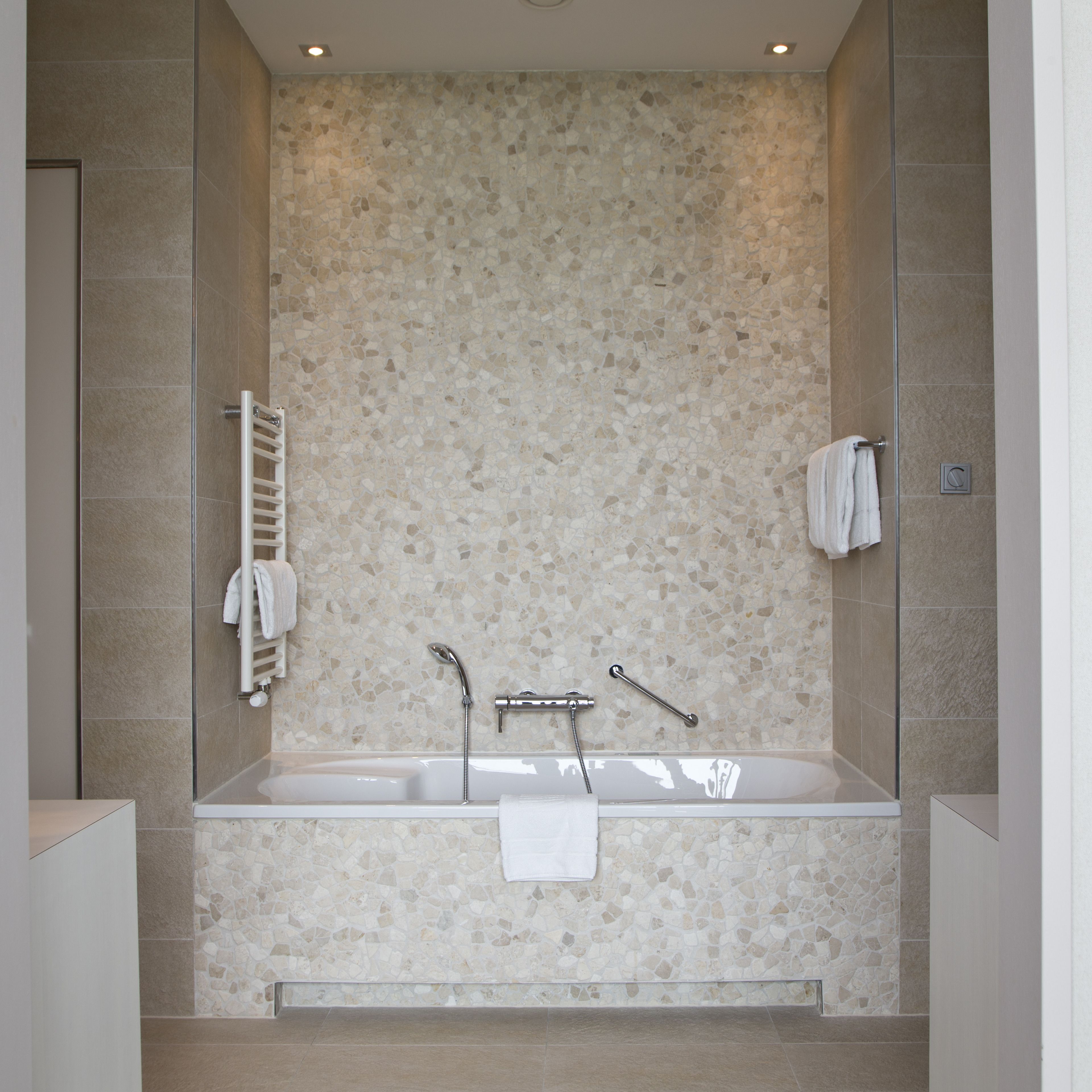 Un baño moderno con una bañera independiente, un cabezal de ducha y un perchero para toallas.