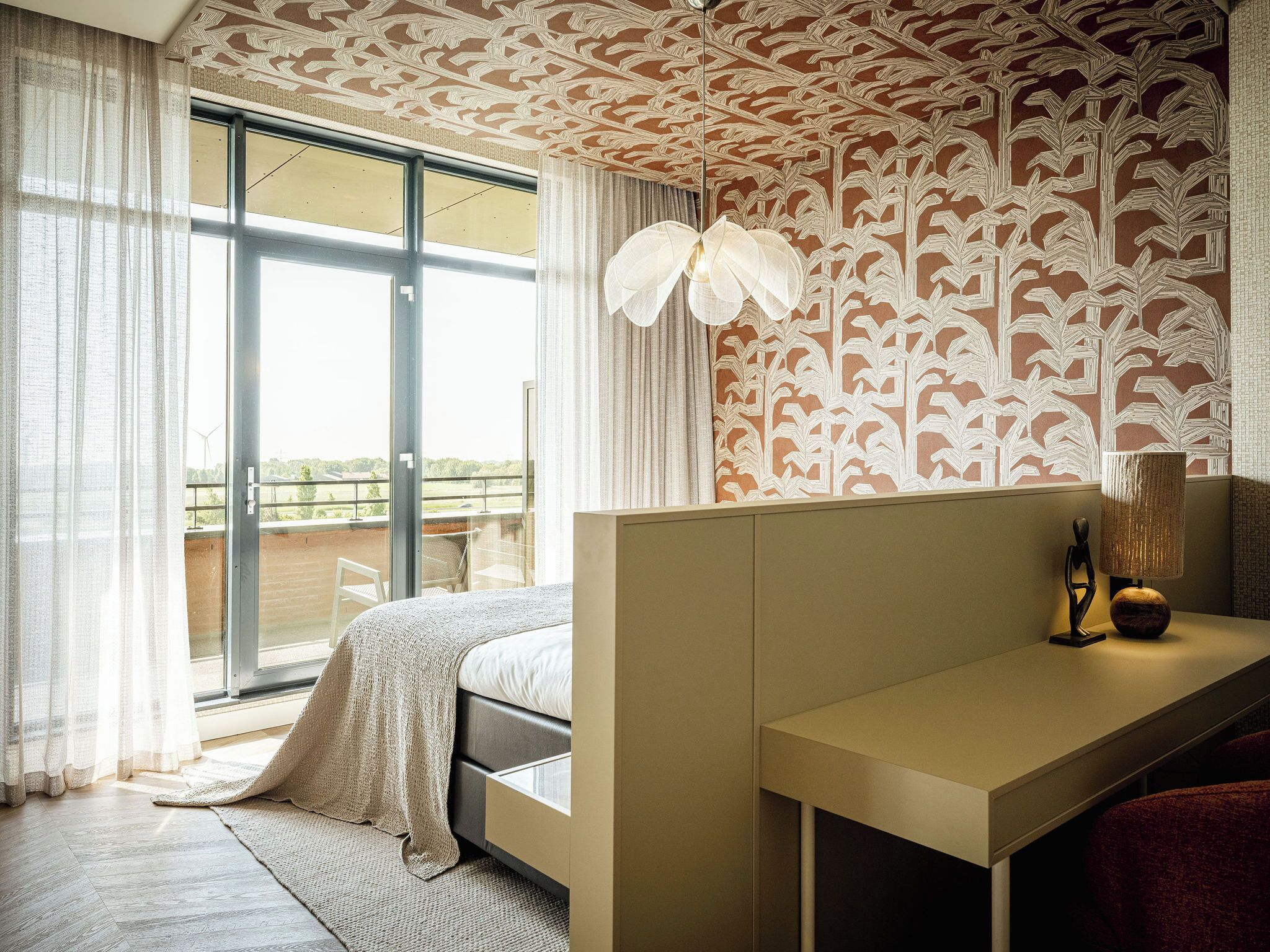 Une chambre moderne dotée d’une grande fenêtre, d’un lit, d’un bureau et d’un motif décoratif au plafond.
