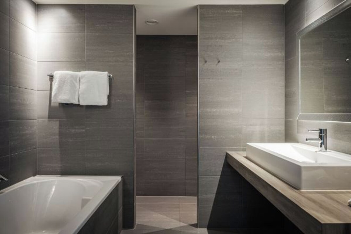 A modern bathroom with a bathtub, a sink, and a large mirror.