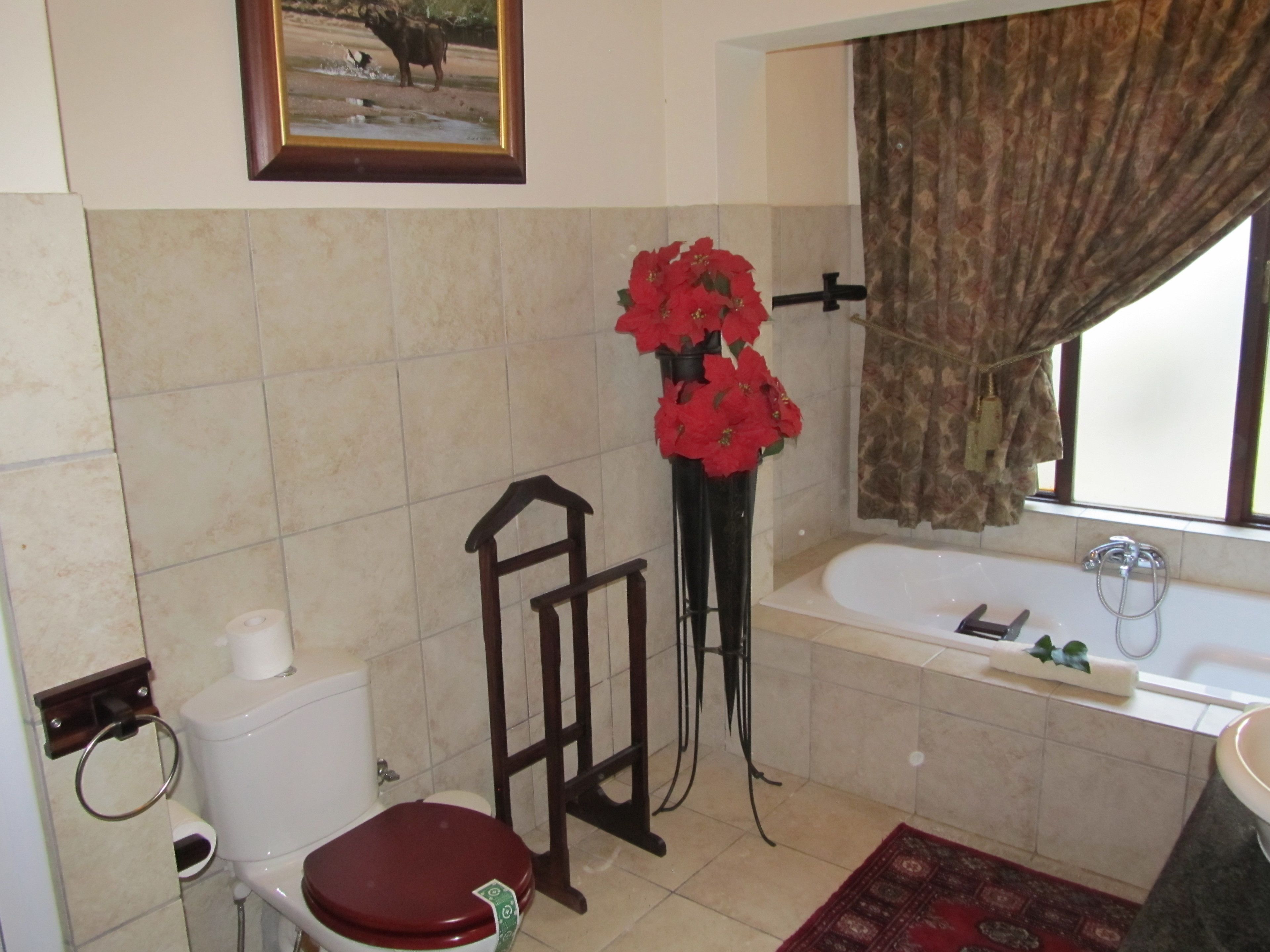 A bathroom with a toilet, bidet, bathtub, and a window with curtains.