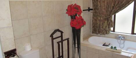 A bathroom with a toilet, bidet, bathtub, and a window with curtains.