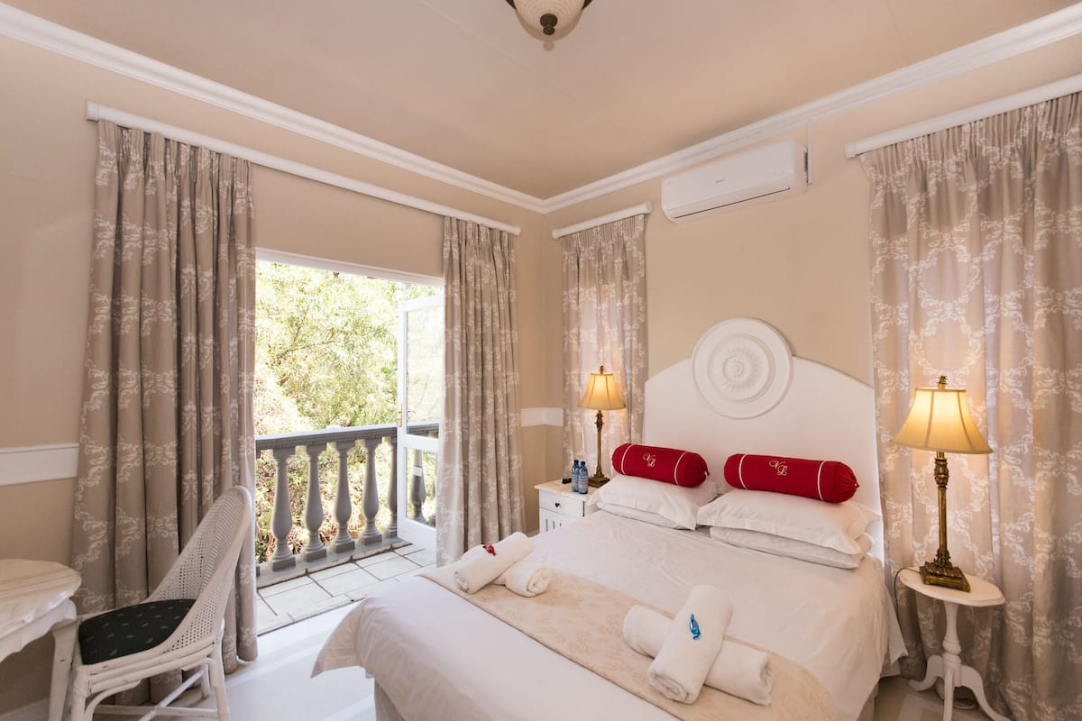 A hotel room with a bed, two bedside tables, a chair, and a balcony.
