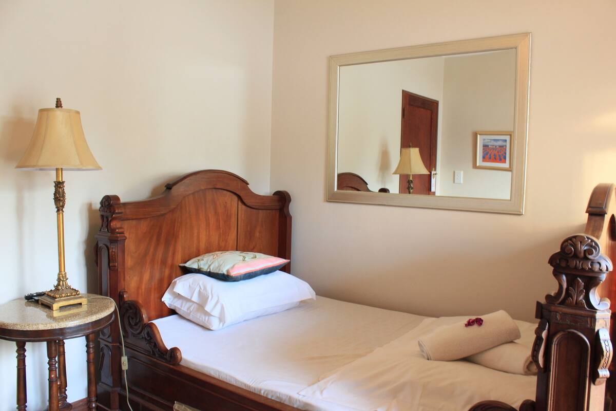 A neatly made bed with white linens, a wooden headboard, and a bedside table with a lamp.