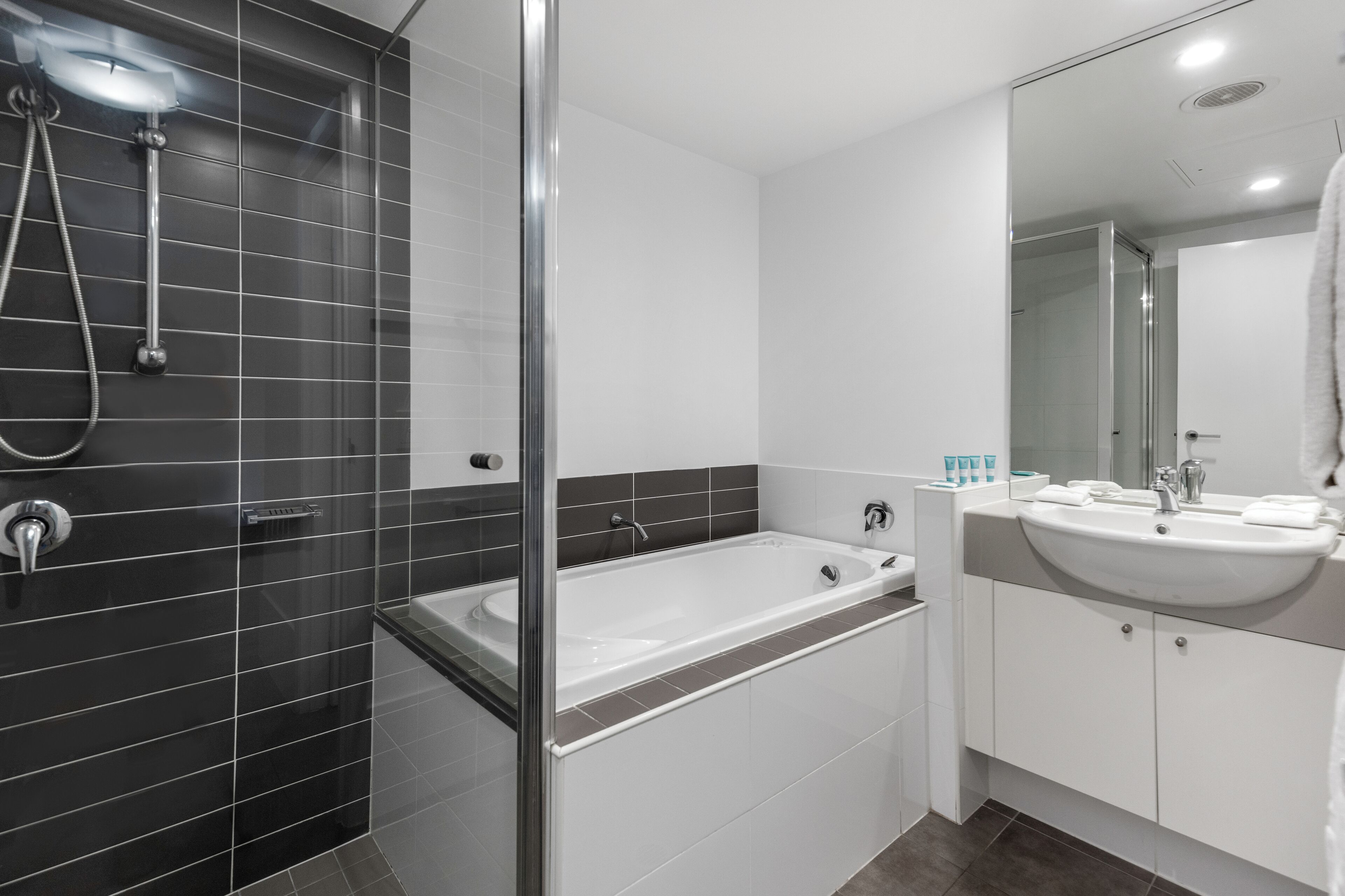 A modern bathroom with a glass-enclosed shower, a freestanding bathtub, and a white sink with a mirror above it.