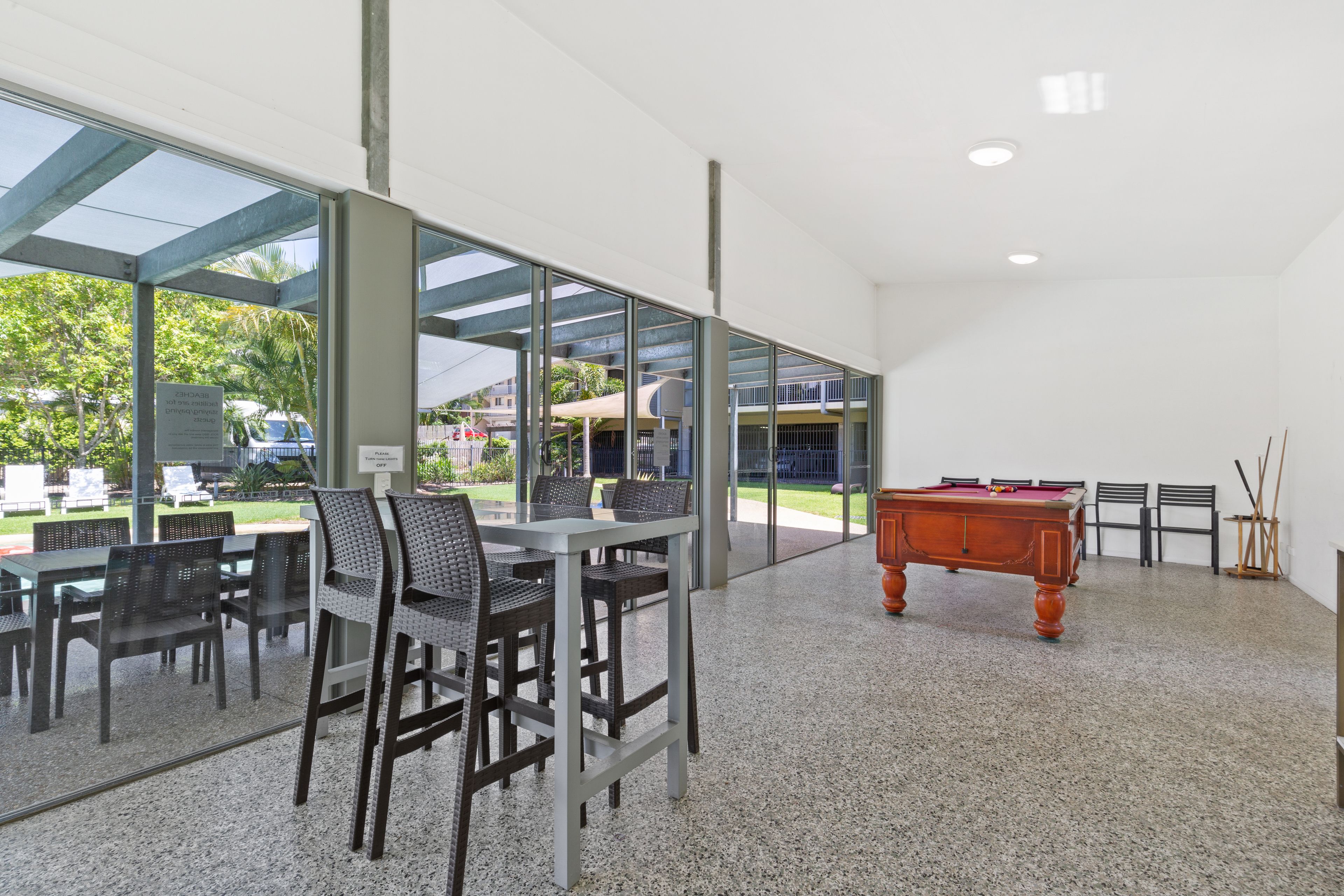 Un espacio interior moderno con mesa de billar, zona de estar y grandes ventanales que ofrecen vistas al exterior.