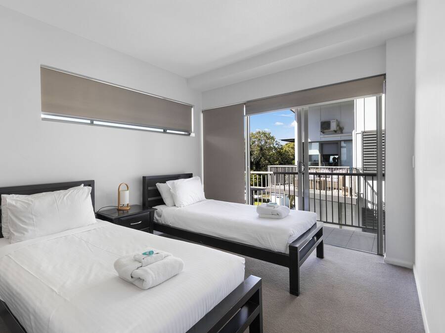 A hotel room with two beds, a balcony with a view, and a small kitchenette.