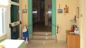 Un couloir avec une arche verte menant à un escalier, un meuble en bois contenant des bouteilles et un tableau encadré accroché au mur.