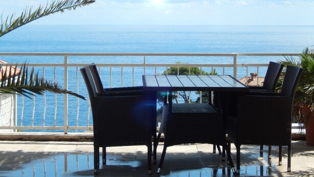 A balcony with a table and chairs overlooking the sea. - Dubrovnik Apartments Kovacec (Dubrovnik)