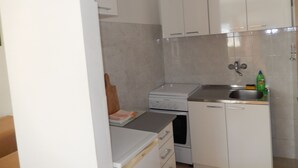 A compact kitchen with white cabinets, a built-in oven, and a stainless steel sink. - Dubrovnik Apartments Kovacec (Dubrovnik)