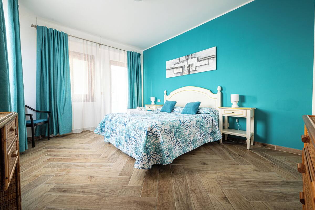 A bedroom with a bed, a nightstand, a chair, and a dresser.