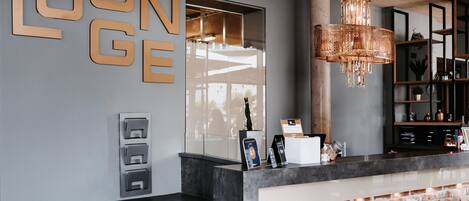 A reception area with a modern design, including a brick accent wall, a hanging light fixture, and a glass partition.