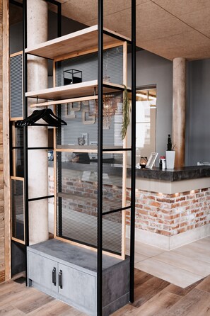 A reception area with a brick counter, a grey cabinet with drawers, and a mesh partition. - Hotel My Place (Lautzenhausen)