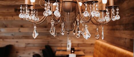 A chandelier with crystal decorations hanging above a wooden dining table with two vases.