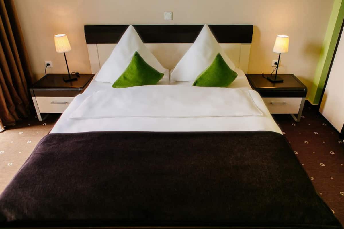 A hotel room with a bed, two nightstands, and two lamps.