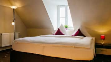 Een slaapkamer met een bed, nachtkastje, lamp, raam en radiator.