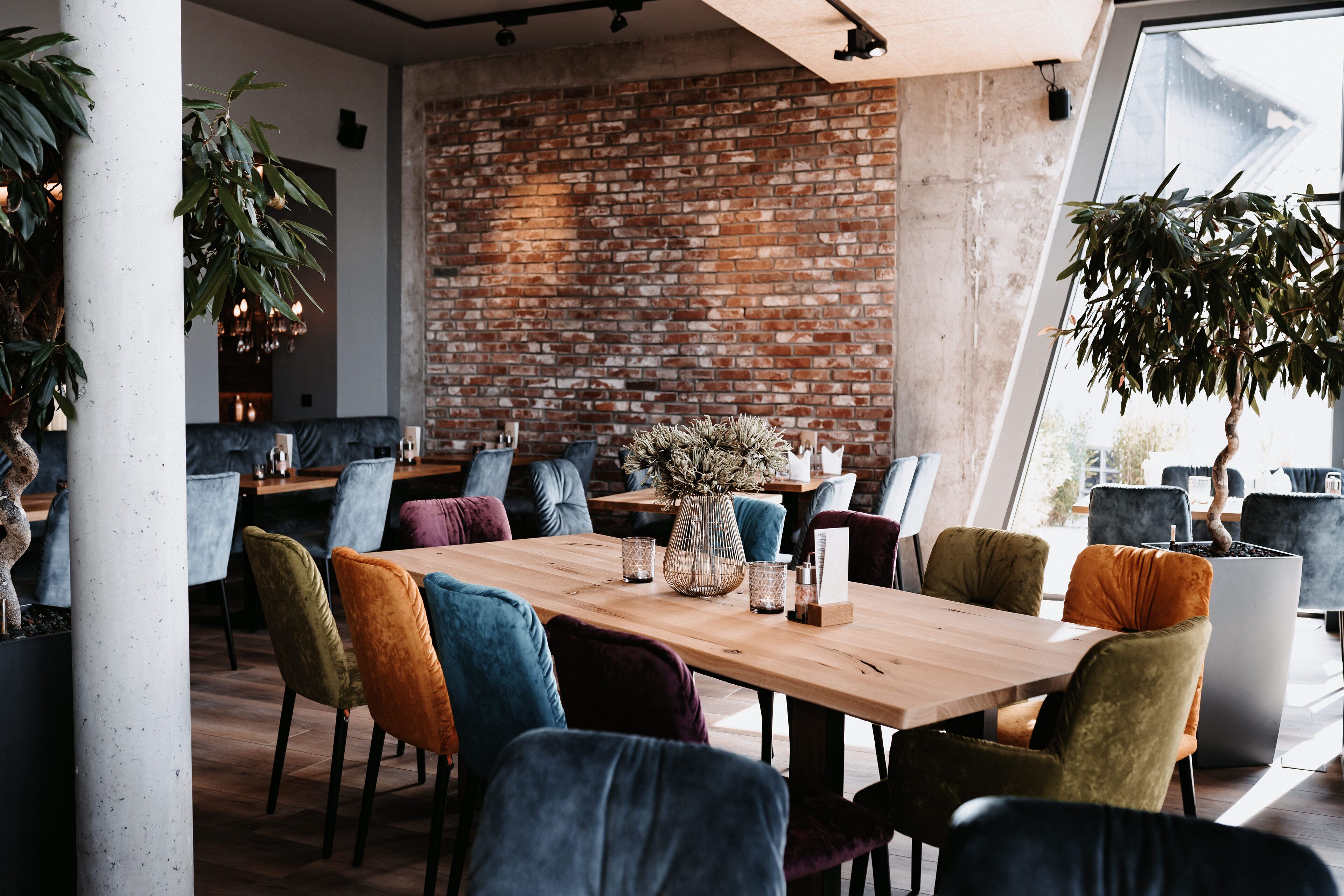 Un comedor moderno con pared de ladrillo, mesa de madera y sillas coloridas.