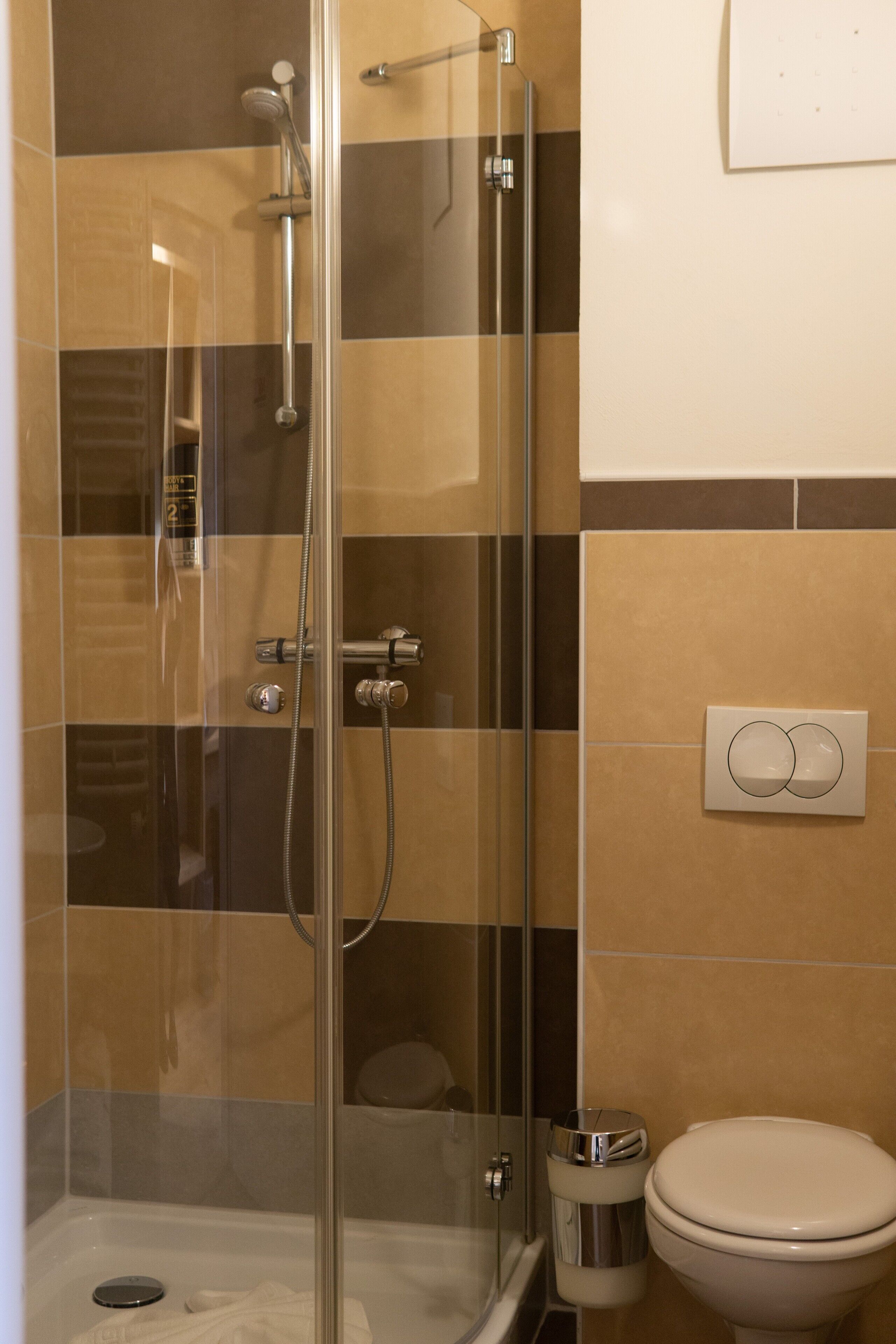 Un baño con ducha de vidrio, inodoro y cubo de basura.