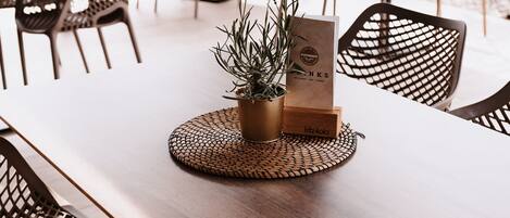 A dining area with a long wooden table, wicker chairs, and a woven placemat.