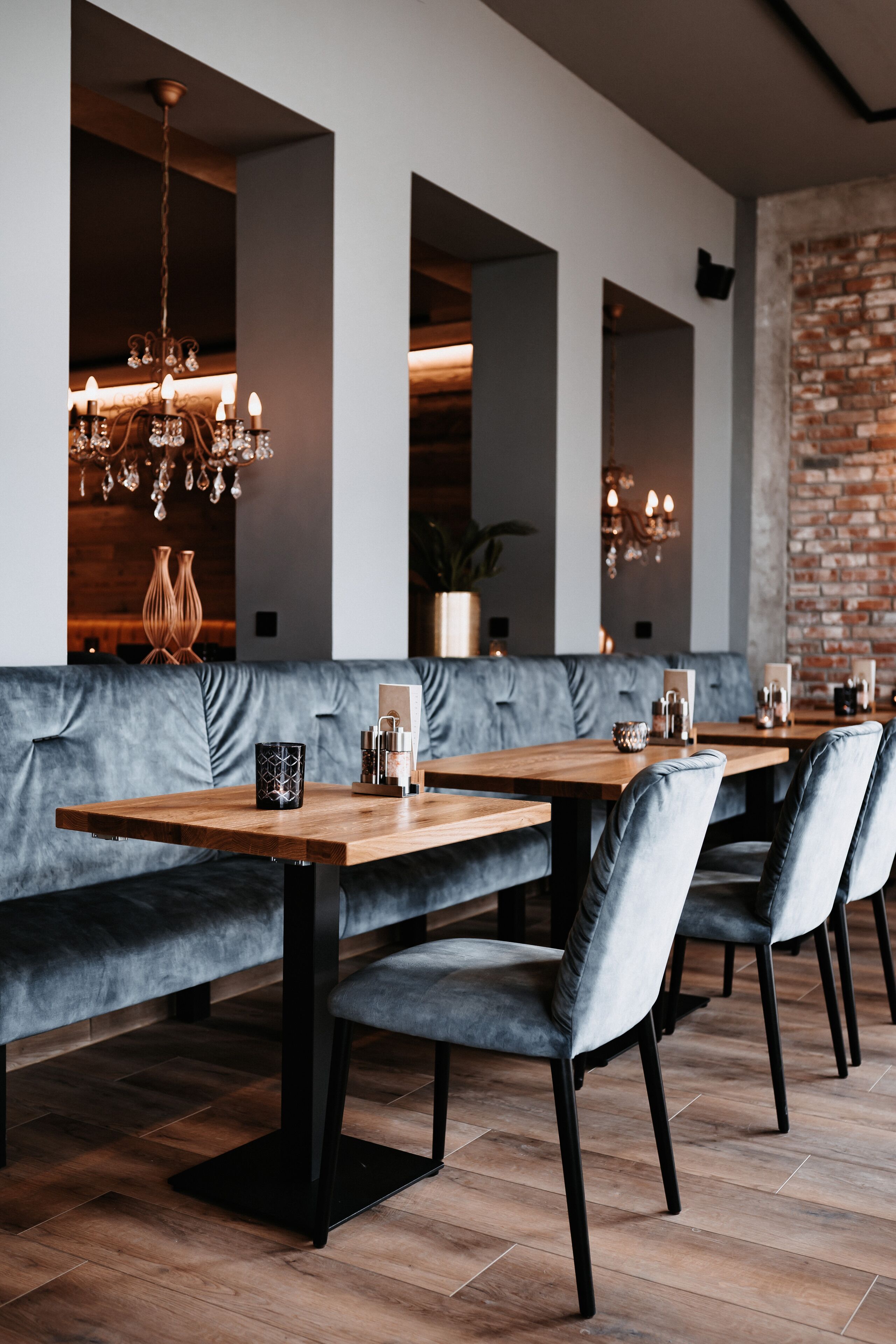 A modern restaurant with wooden tables and grey upholstered benches.