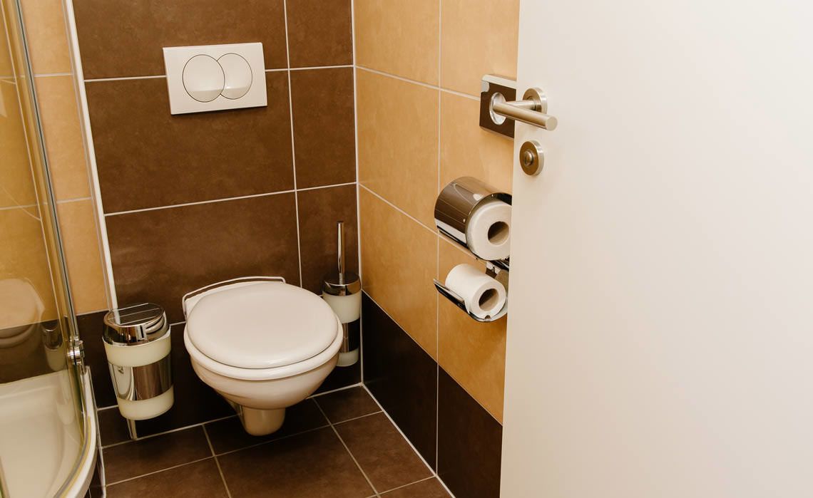 A bathroom with a toilet, bidet, and toilet paper dispenser.