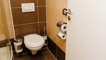 A bathroom with a toilet, bidet, and toilet paper dispenser.