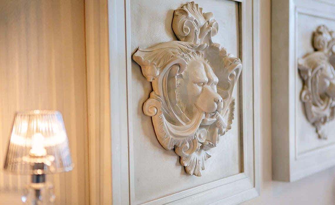 Un mur orné de sculptures et une lampe en premier plan.