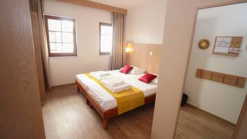 A hotel room with a wooden bed, a yellow bedspread, and a mirror on one wall.