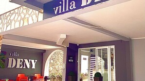 The exterior of a hotel named 'villa DENY' with a red carpet entrance, outdoor seating area, and a stone facade. - "VILLA DENY" Boutique HOTEL - with free parking (Mostar)