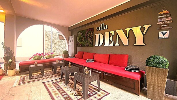 A cozy lounge area with a red sofa, small tables, and a large wall sign reading 'villa DENY'. - "VILLA DENY" Boutique HOTEL - with free parking (Mostar)