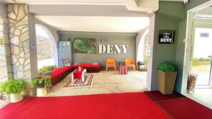 A cozy reception area with a red carpet, a sofa, and two chairs. A sign on the wall reads "villa DENY". - "VILLA DENY" Boutique HOTEL - with free parking (Mostar)