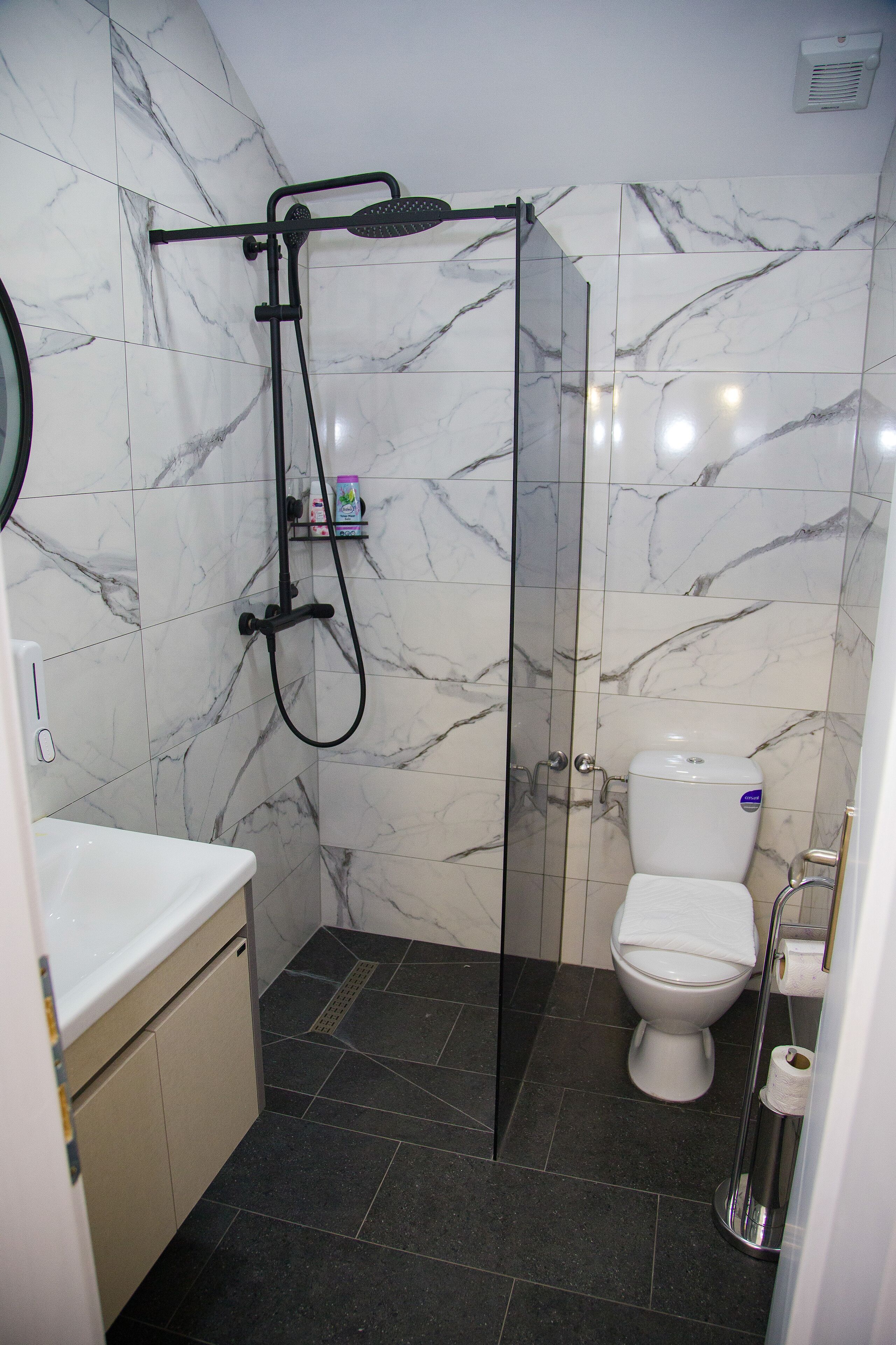 A bathroom with a glass-enclosed shower, a toilet, and a sink.