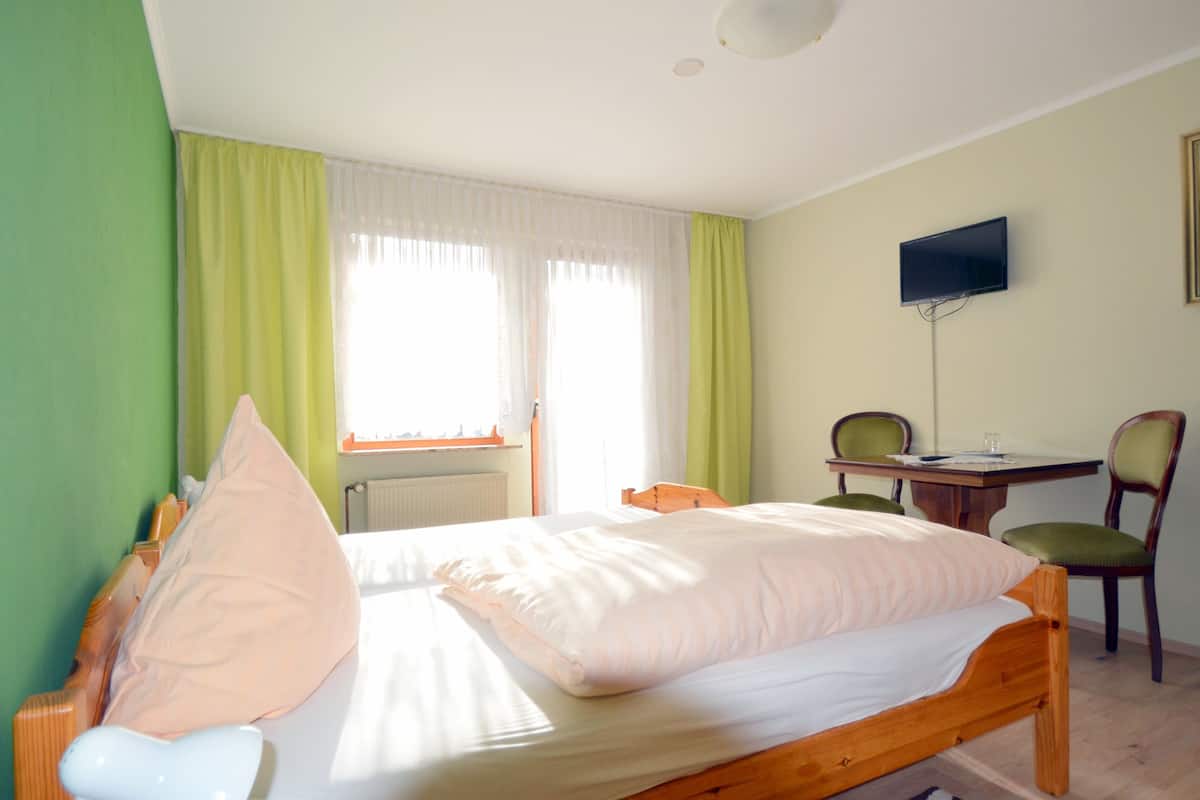 A bedroom with a bed, a desk, and a chair.