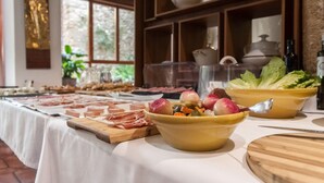 A buffet table with various meats, vegetables, and a bowl of salad. - Hotel Nou Romà (Denia)