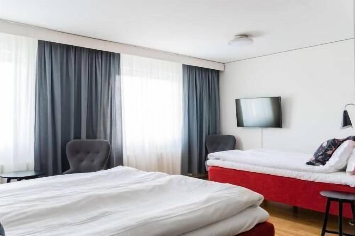 A hotel room with two beds, a TV, a chair, and a small table.