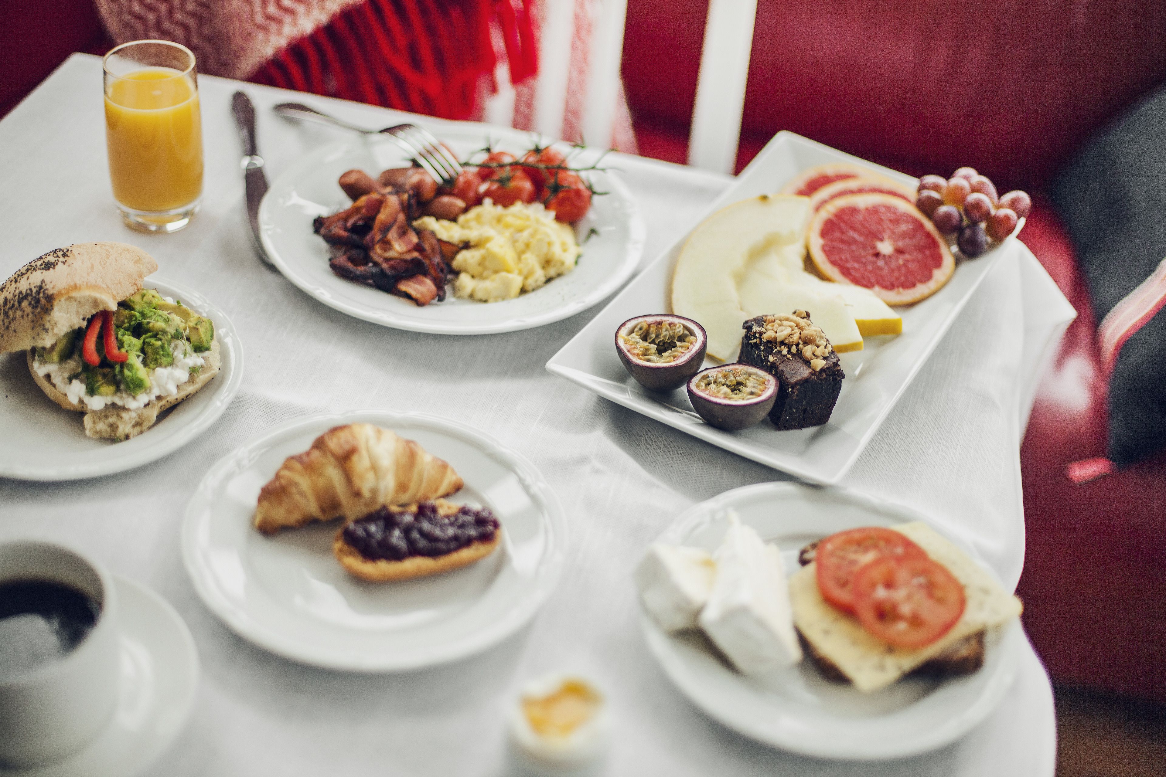 Een ontbijttafel met diverse gerechten, waaronder eieren, spek, toast en fruit.