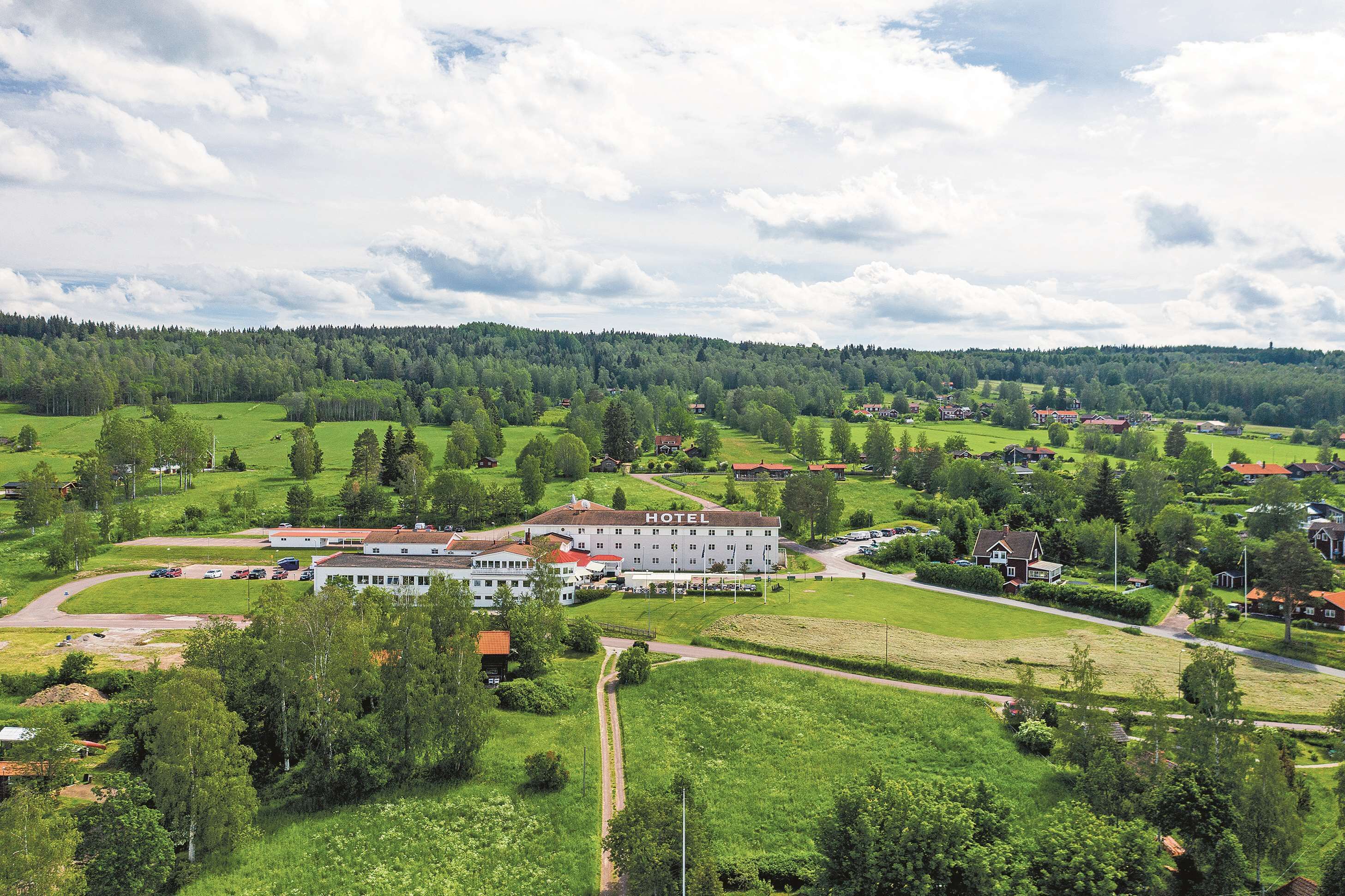 Um hotel rodeado por campos verdes e árvores, com vista desobstruída para a paisagem circundante.