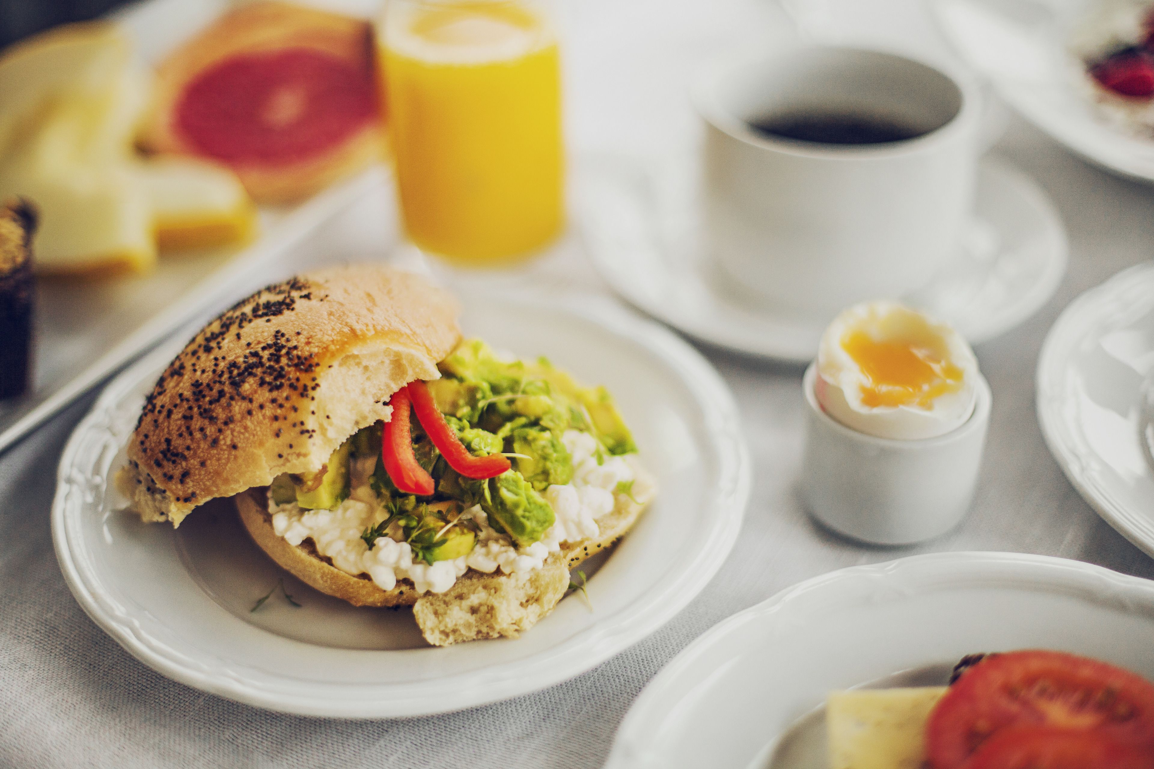 A breakfast setting with a sandwich, a cup of coffee, and a small container of butter.