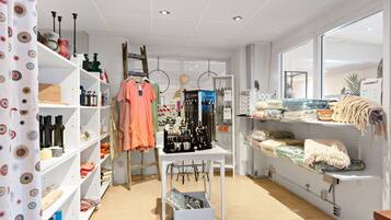 A well-organized retail store with shelves stocked with various items, a display table with accessories, and a window providing natural light.