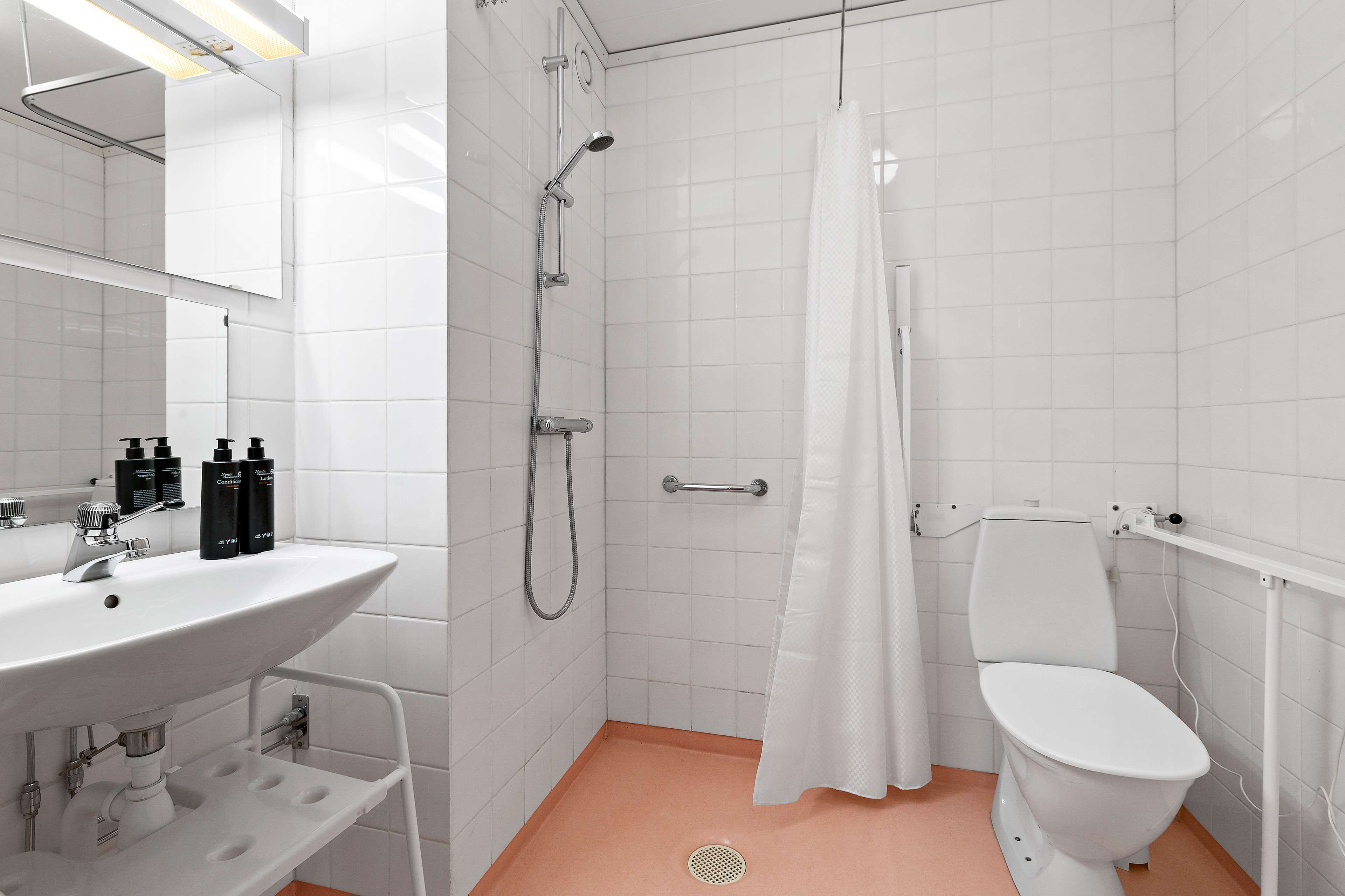 A bathroom with a white sink, mirror, shower, and toilet.