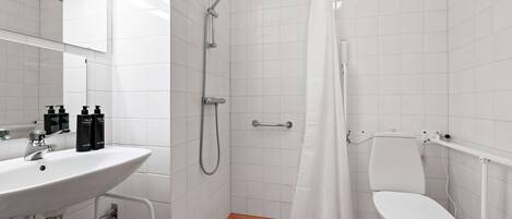 A bathroom with a white sink, mirror, shower, and toilet.