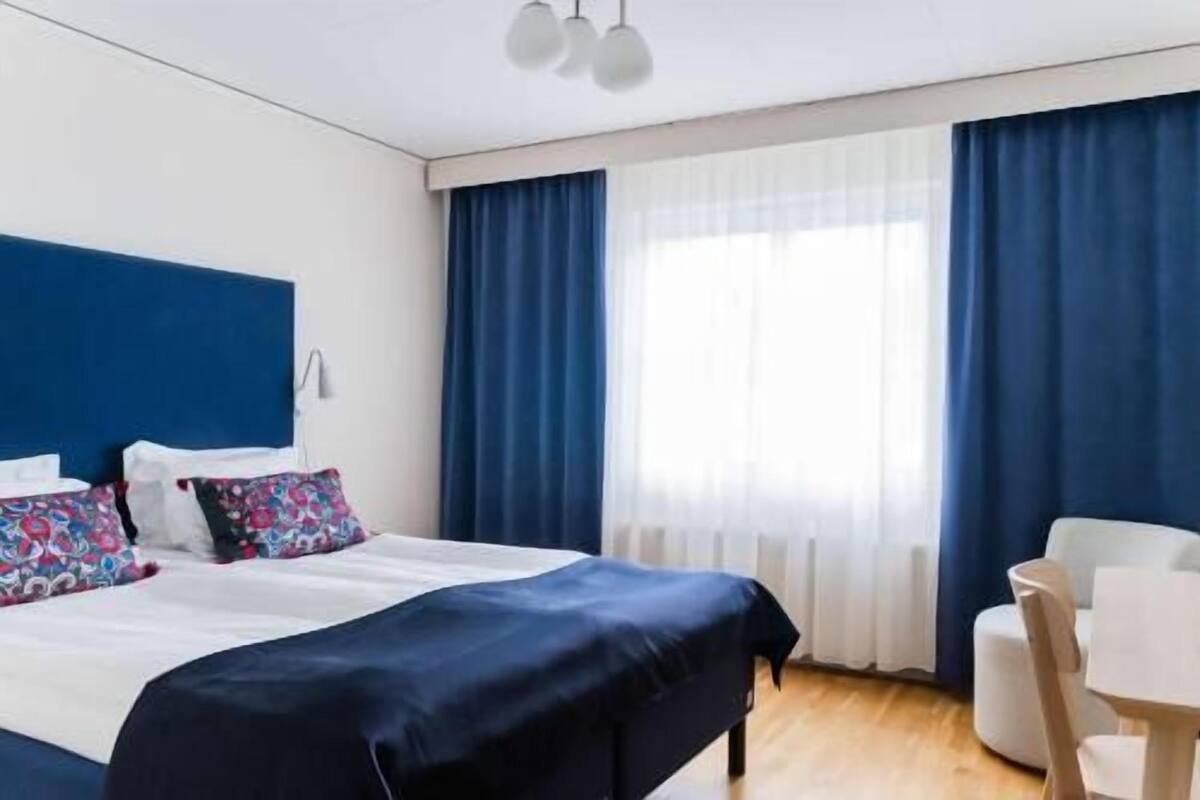 A hotel room with a bed, a desk, and a chair.