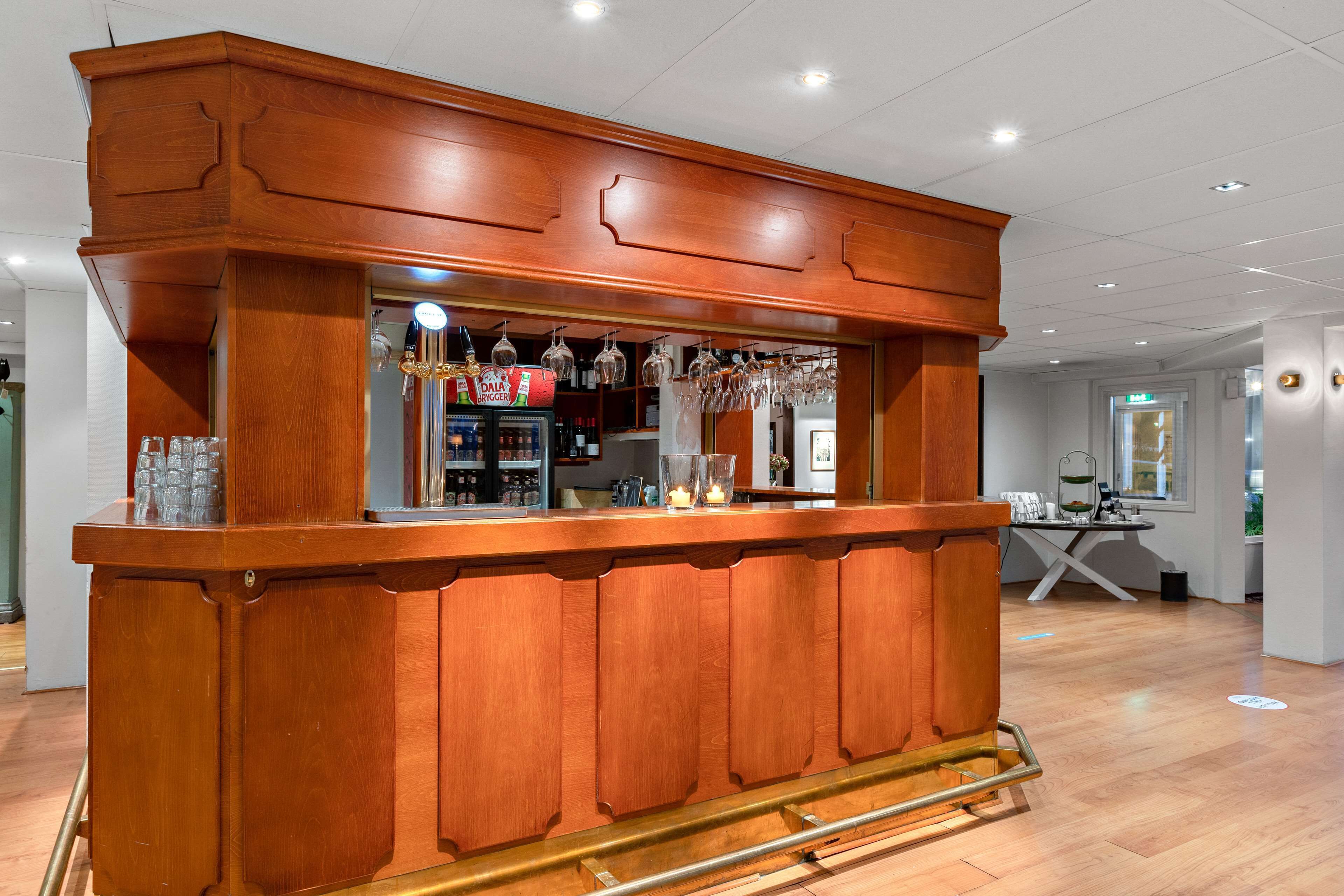 A wooden bar area with a counter, glasses, and a beverage dispenser.