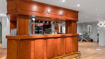 A wooden bar area with a counter, glasses, and a beverage dispenser.