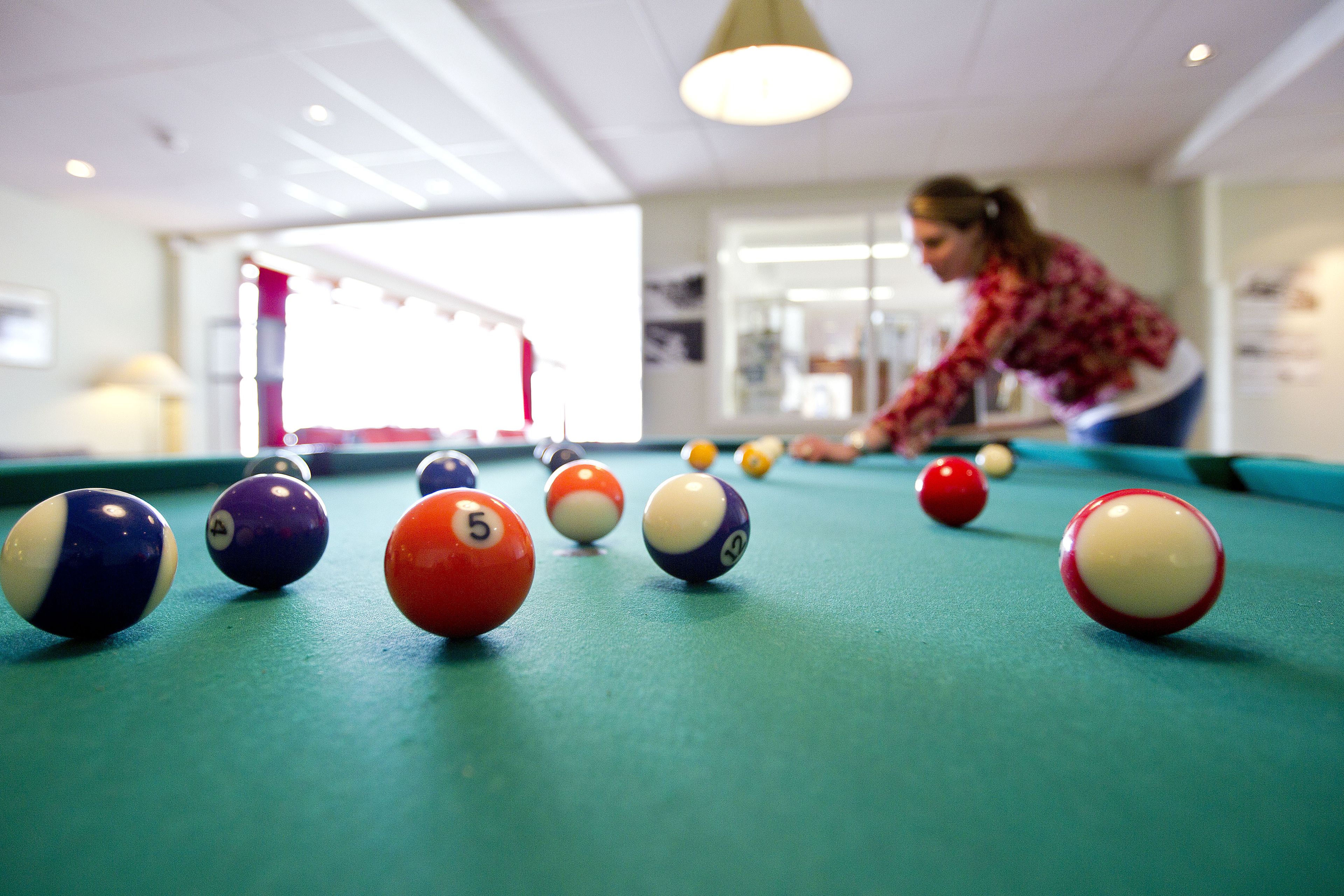 Une table de billard avec des billes numérotées et une personne qui joue.