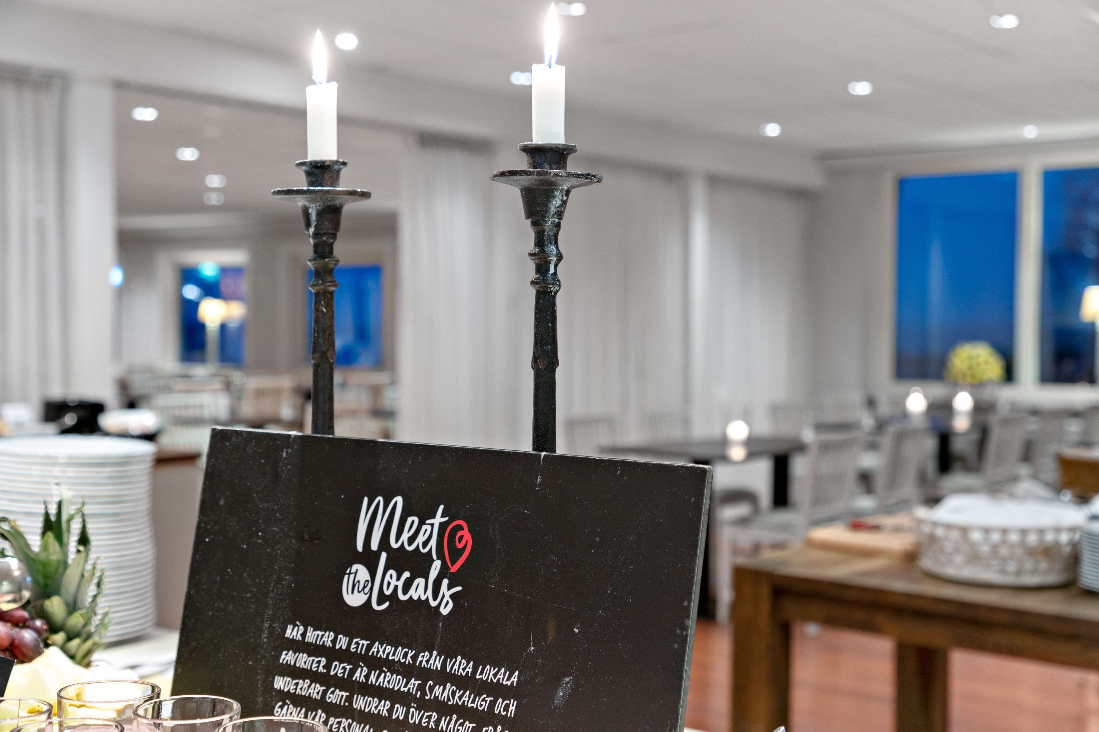 Un cartello con su scritto 'Meet the locals' e candele su un tavolo in sala ristorante di un hotel.